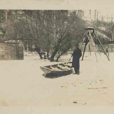Man stands next to rowboat on shore of Highland Park