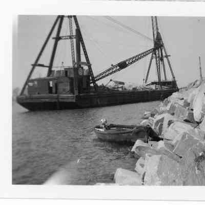 Outboard boat docked in front of underway barge
