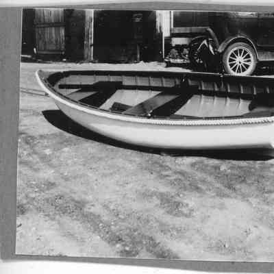 Rowboat on ground with cars in background