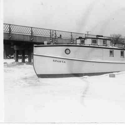 Fishing tug Sparta docked in icy water next to bridge