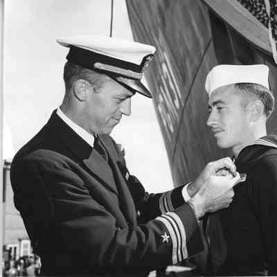 Officer pinning medal on sailor next to PGM-31