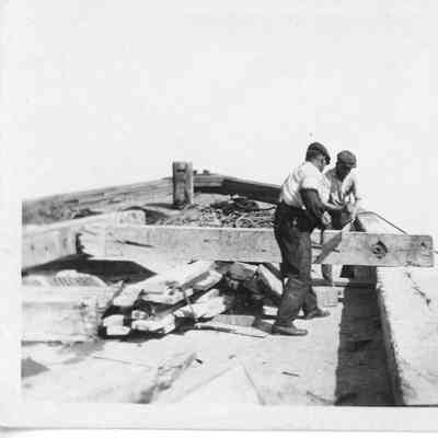 Two men pulling rope from deck of vessel