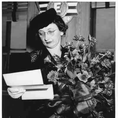 Mrs. John Butterweck holding roses and reading letter