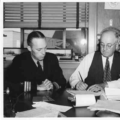 L.D. Smith and man sitting at table signing document