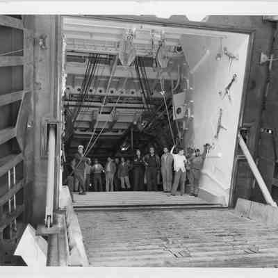Group of men standing inside of LST-1166 with hatch open, September 4, 1953