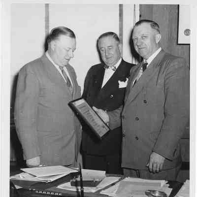 C. Ray Christianson with plaque in hand with two men
