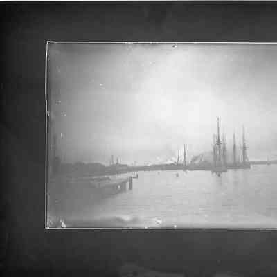 masted vessles in water with dock on left