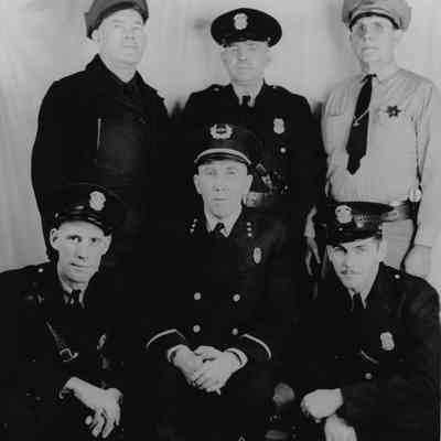 Kennewick Police Department Officers identified on back of photo. Picture taken at end of WWII, probably about 1945. In uniform bottom row: (left to right) John Dickinson, Mitch Kershaw, Ward Rupp. Top Row: Walt Billingsley, William Foraker, Ted Persinger