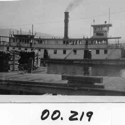 Flyer steamer in dock next to lumber barge.