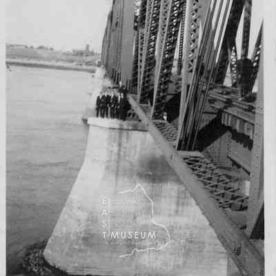 People in Suits on Rail Bridge
