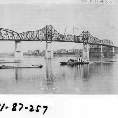View of the final construction phase of the "Old" Pasco-Kennewick Bridge. Dedication services were held for this privately owned bridge 10/21/1922 after which the ferry shown in the picture ceased to operate. Toll Charges for the bridge on way, 10 cents per passenger and 75 cents per car..