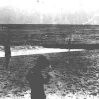 B+W negative image of a seashore near a groin with children, no place, no date, ca. 1900-1910.