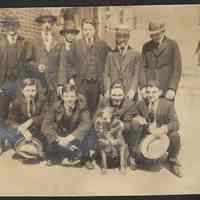 Digital image of photo of ten men in suits posed with a dog on a city street, no place (Hoboken?), no date, circa 1910-1915.