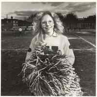 B+W photo of Cynthia Lisa, a Hoboken High School cheerleader performing at a football game, JFK Stadium, Hoboken, no date, [1976].