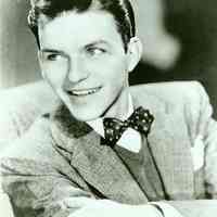 Black-and-white photo of a young Frank Sinatra in a suit with sweater vest and bowtie, no place, no date, ca. 1939.