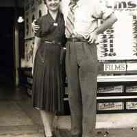 B+W photo of a woman and man posed in front of the exterior of Baron