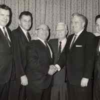 B+W photo of John J. Grogan (2nd from right) shaking hands with man; four other men posed with them, (Hoboken), no date, ca. 1965