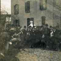 Sepia-tone photo of group posed on street with dog & fire engine pumper, Hoboken, n.d., ca. 1905-1915.