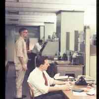 Color slide of three men in an office.