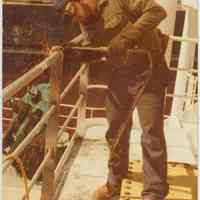 Color photo of Luis Denis using a torch on a ship railing at the Bethlehem Steel Shipyard, Hoboken Division, no date, ca. 1980.