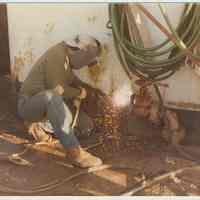 Color photo of Luis Denis using a torch on a ship at the Bethlehem Steel Shipyard, Hoboken Division, no date, ca. 1980.