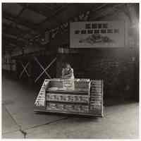 B+W photo of a boy selling official souvenir programs from a cart inside the train terminal platform area, Hoboken, no date, [1976].