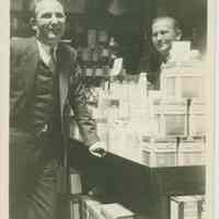 Sepia-tone photo of two men posed in the the interior of Baron