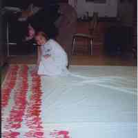 Color photo of Amy Young and female Glenwood Primary School student painting a handprint on the Georgia Children