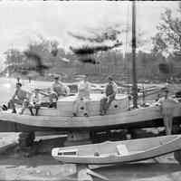          men and boats on riverfront near New Jersey Yacht Club clubhouse.
   