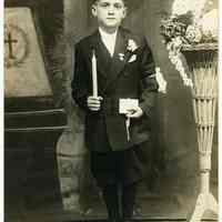 Sepia-tone photo of boy posed in studio with church interior backdrop, Hoboken, n.d., ca. 1910-1925.