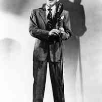 Black-and-white photo of a young Frank Sinatra posed at a CBS microphone, no place, no date, ca. 1940.