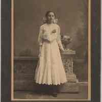 Sepia-tone photo of young woman holding book posed in photographer