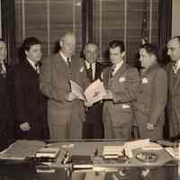 Digital image of sepia-tone photo of Mayor Fred DeSapio with City officials and man presenting document, Hoboken, no date, ca. 1947 -1950.
