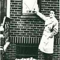 Black-and-white photocopy of photo of Joseph Ratti pointing to a Victory flag in the window at 721 Adams St., Hoboken, 1944.