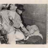 B+W photo of physician treating an unconcious fireman at Holland Tunnel after explosion, May 13, 1949.