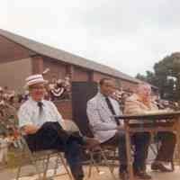 Color photo of three dignitaries seated on the dais at Baseball Day Ceremonies, 1976.