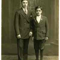 Sepia-tone photo of man & boy posed in studio with church backdrop, Hoboken, n.d., ca. late 1910s through 1920s.