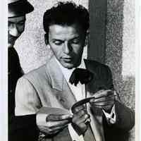 Sinatra photo: Frank Sinatra with floppy bowtie talking to security guard or police officer, Universal City, CA?; Copyright 1946 Universal Pictures Co.
