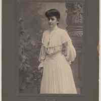 Mounted photo of young woman in fine dress posed in studio, Hoboken, n.d., ca. 1895-1900.