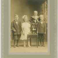 Sepia-tone photo portrait of 4 children posed in photographer