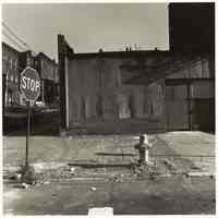 B+W photo of a street corner with stop sign, fire hydrant and empty corner lot, Hoboken, no date, [1976].