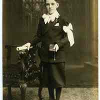Sepia-tone photo of boy posed in studio with church backdrop, Hoboken, n.d., ca. late 1910s through 1920s.
