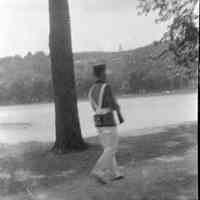 B+W negative image of an of an unidentified soldier in uniform marching on a riverbank, no place, no date, ca. 190