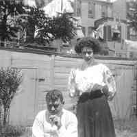 B+W negative images of unidentified man & woman in a backyard, no place, no date, ca. 190