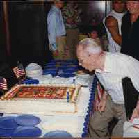 Color photo of George Kirchgessner blowing out candles on a cake celebrating 98th anniversary of United Decorating Co., Hoboken, June 27, 1997.