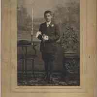 Sepia-tone photo of an unidentified boy with catechism and rosary beads posed in photo studio, Hoboken, no date, ca. 1900.