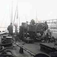 Sepia-tone photo of men working on the deck of an unidentified vessel believed to be docked at the Hoboken piers, Hoboken?, no date, ca. 1916-1918.