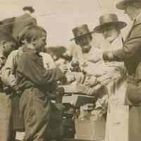 Sepia-tone 8" x 10" group photo of Red Cross volunteers giving toys to Russian refugee children on their way home, Hoboken?, 1920.