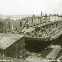 Sepia-tone photo of Union Dry Dock & Repair Co. workers repairing transfer car float barge No. 28 in dry dock, Weehawken, N.J., no date, ca. 1920