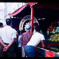 Color slide of a group of people in front of a game stall at a street fair.